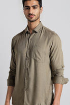 Man wearing a brown button-up shirt against a plain background