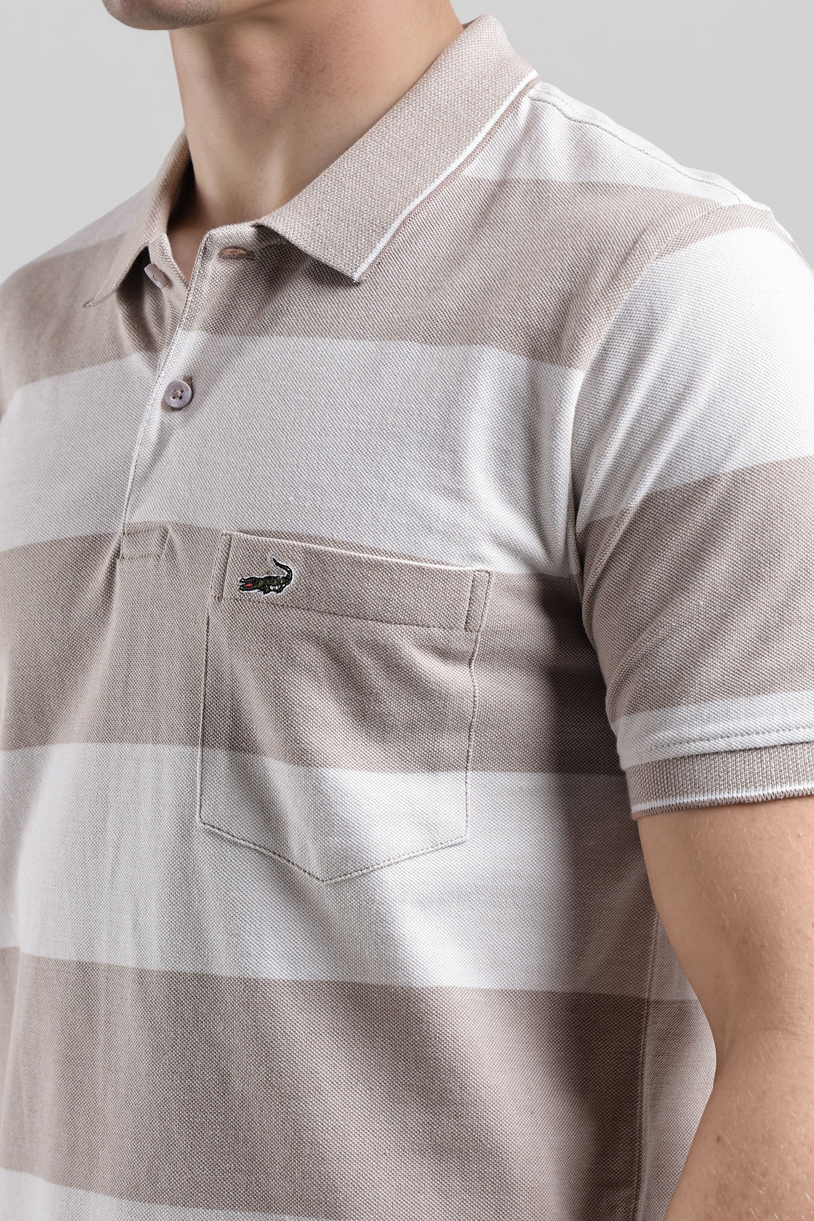 Close-up of a brown and white striped polo shirt with a brand logo on a light gray background