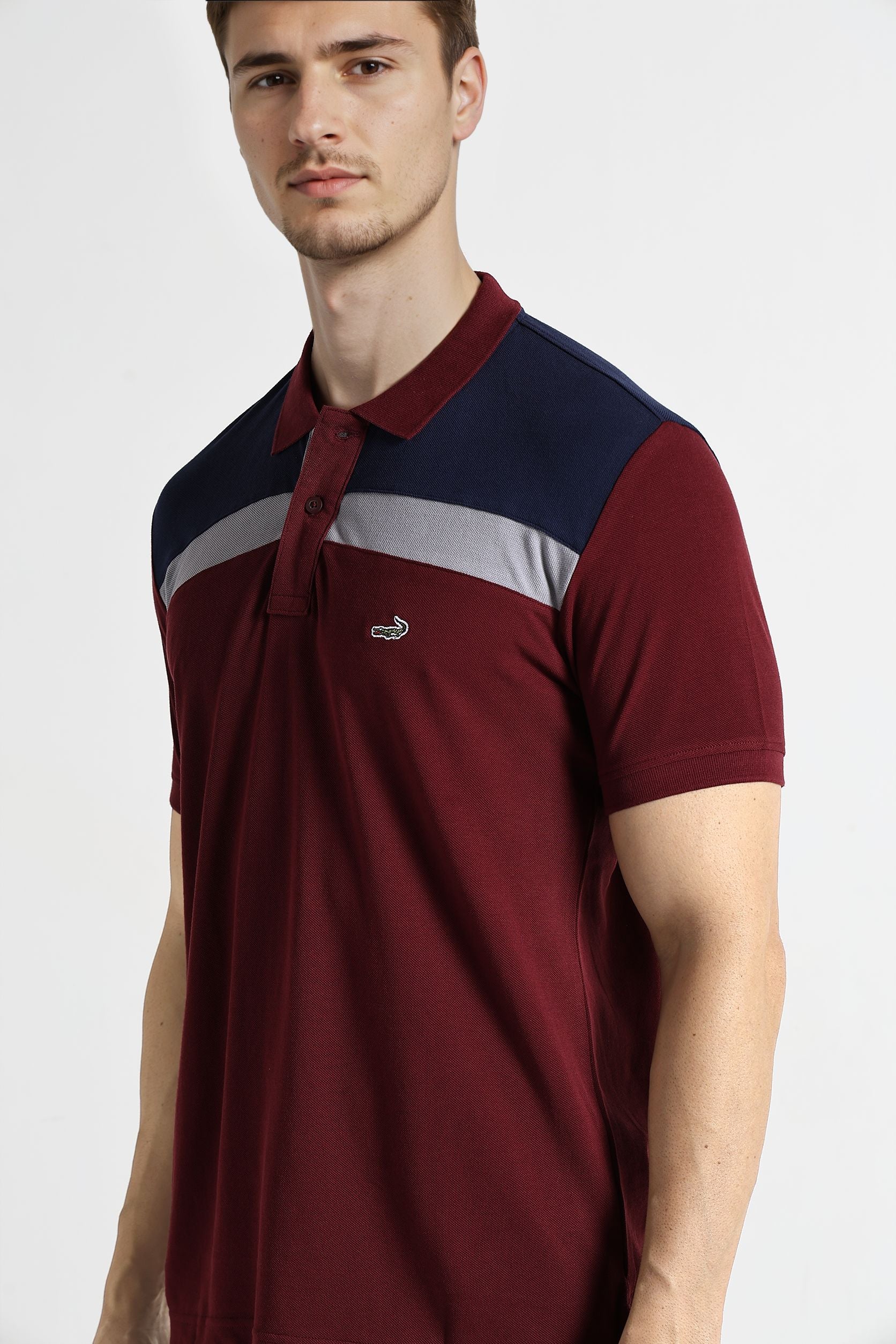 Man wearing a maroon and navy polo shirt with a logo on a white background