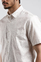 Man wearing a light-colored short-sleeve shirt against a plain background