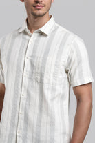 Man wearing a white and gray striped short-sleeve shirt against a gray background