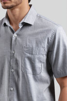 Close-up of a person wearing a gray short-sleeve shirt with a collar and pocket.