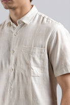 Close-up of a person wearing a beige checkered shirt with a plain background
