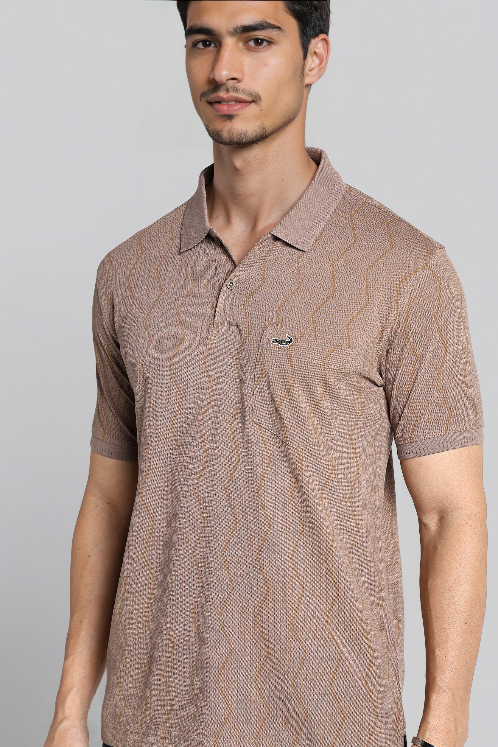 Man wearing a brown patterned polo shirt against a gray background