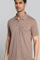 Man wearing a brown patterned polo shirt against a gray background