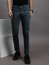 Man wearing a green teal green solid mid rise slim fit jean with casual styling on a gray background