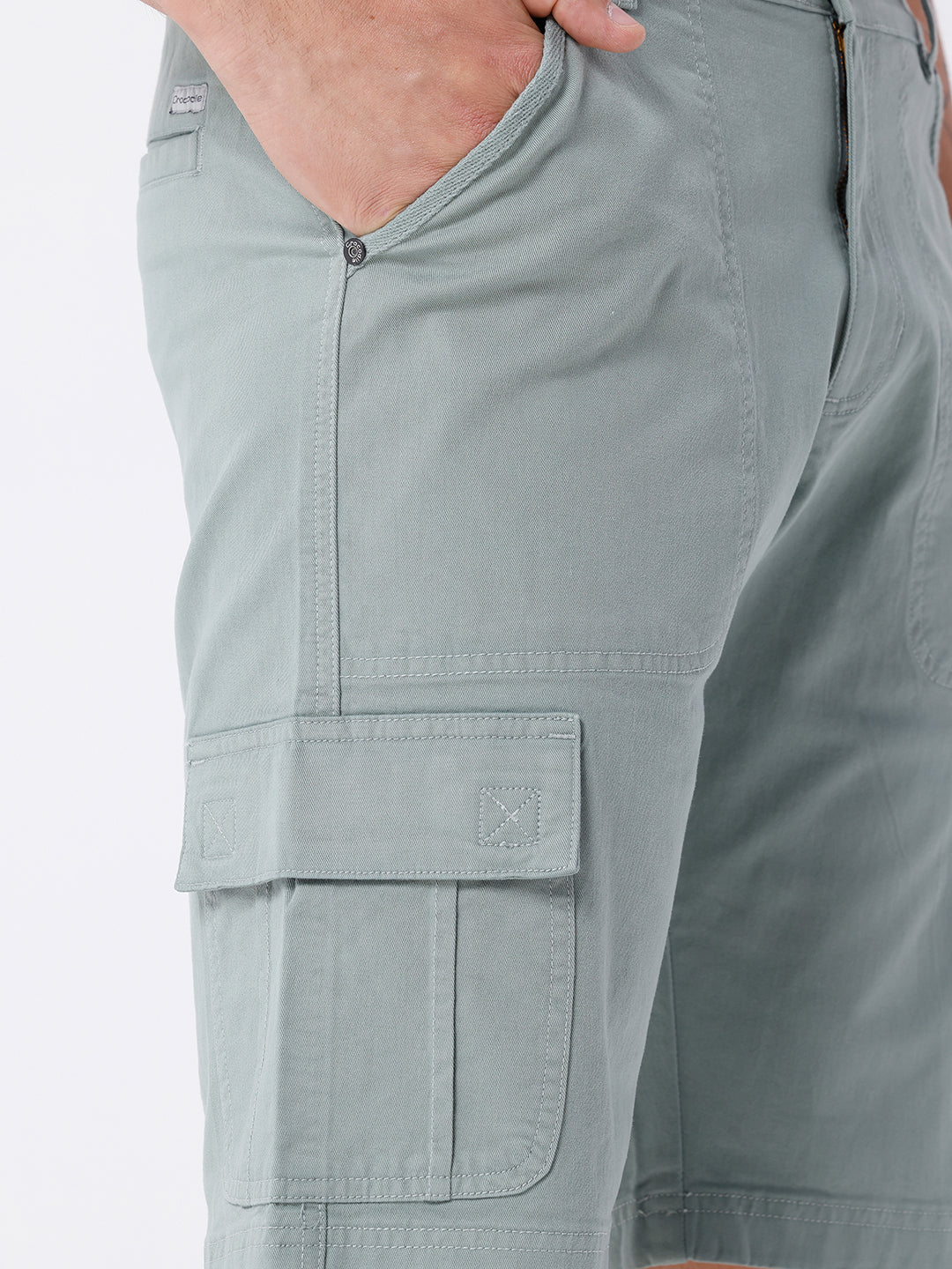 Man wearing a olive garment dyed cargo shorts in olive on a light gray background
