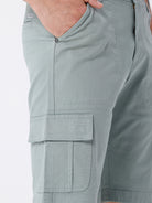 Man wearing a olive garment dyed cargo shorts in olive on a light gray background