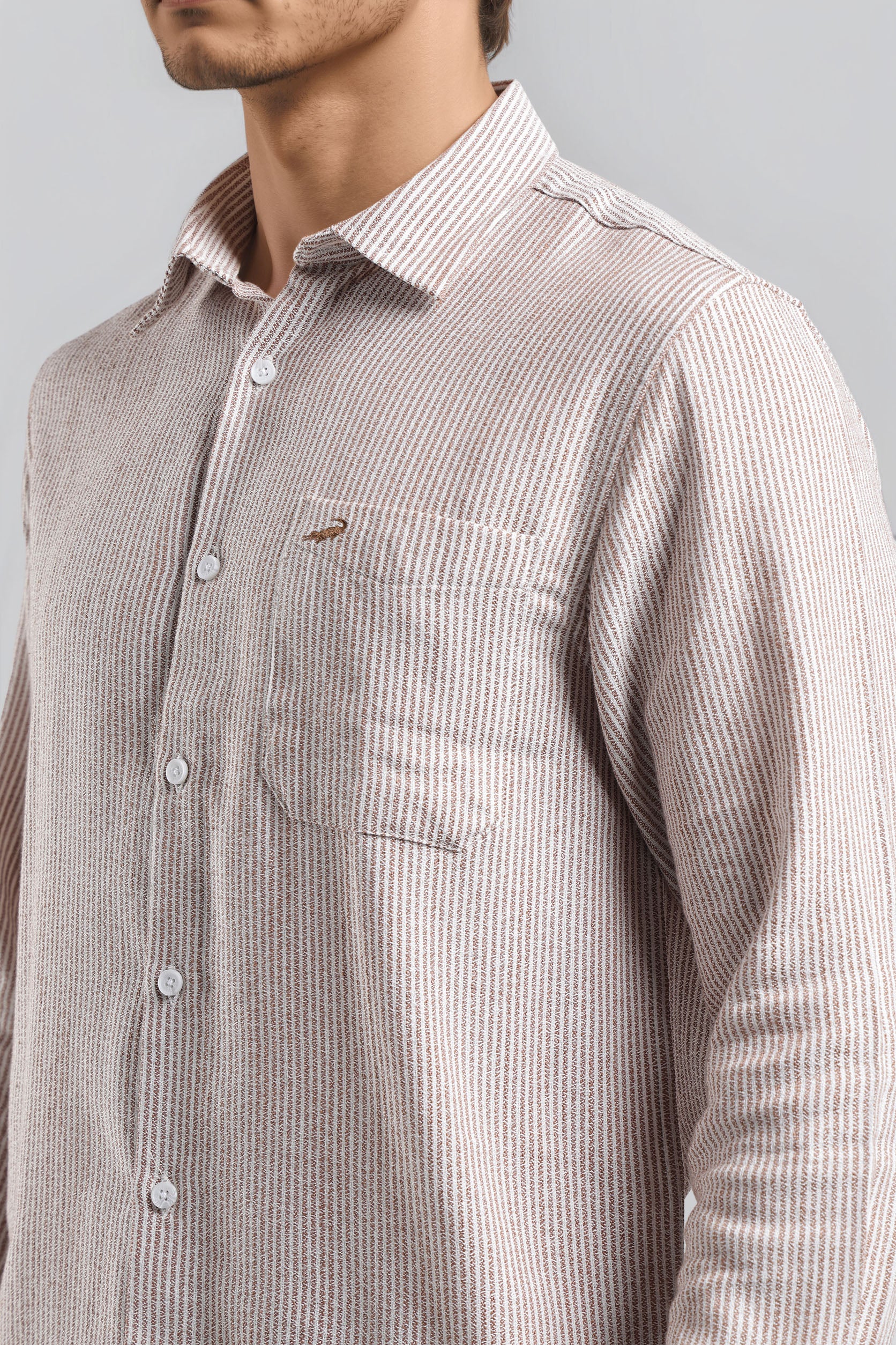 Man wearing a brown striped shirt against a gray background