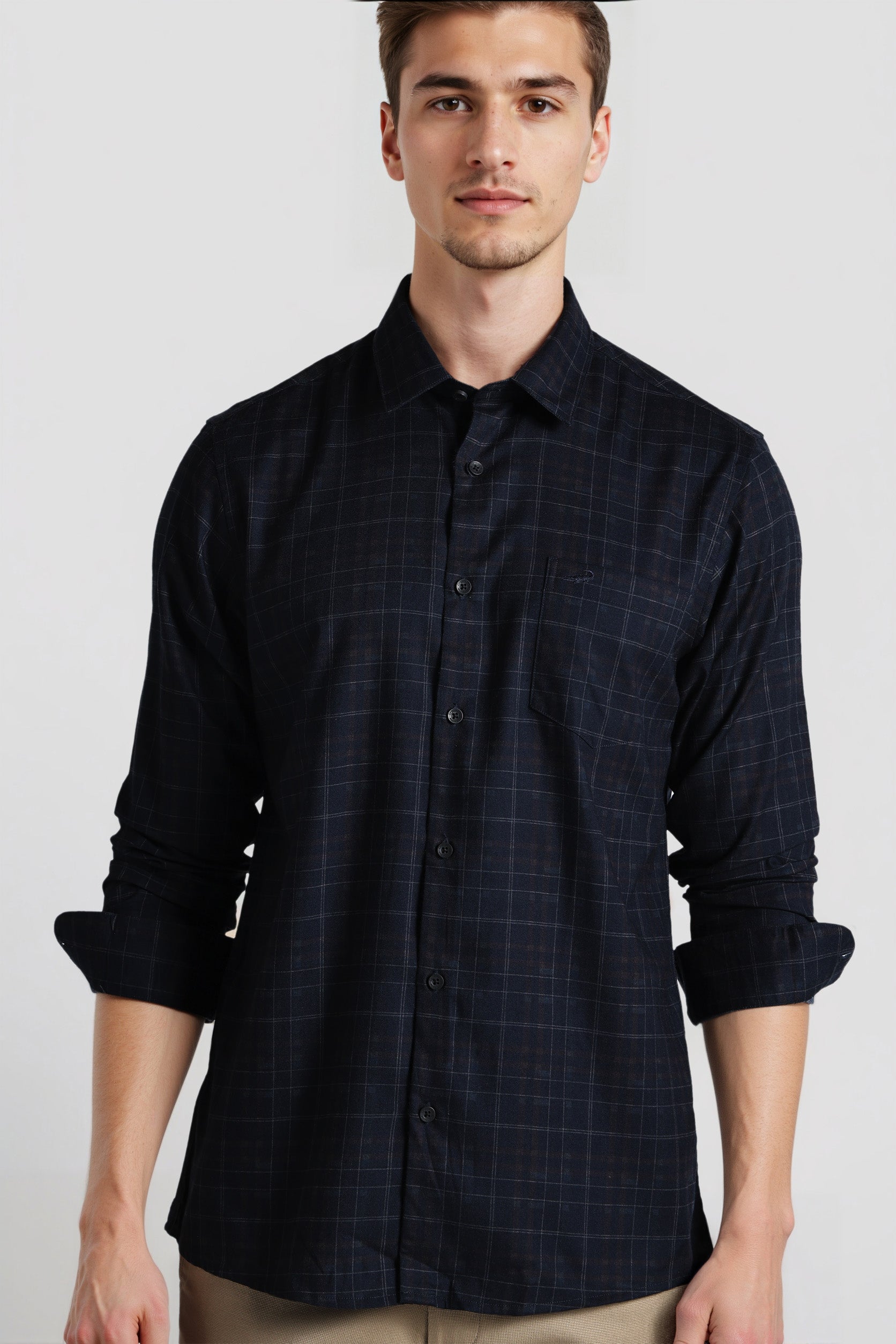 Man wearing a dark blue checkered shirt against a plain background