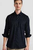 Man wearing a dark blue checkered shirt against a plain background