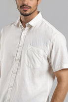 Man wearing a white short-sleeve shirt against a gray background