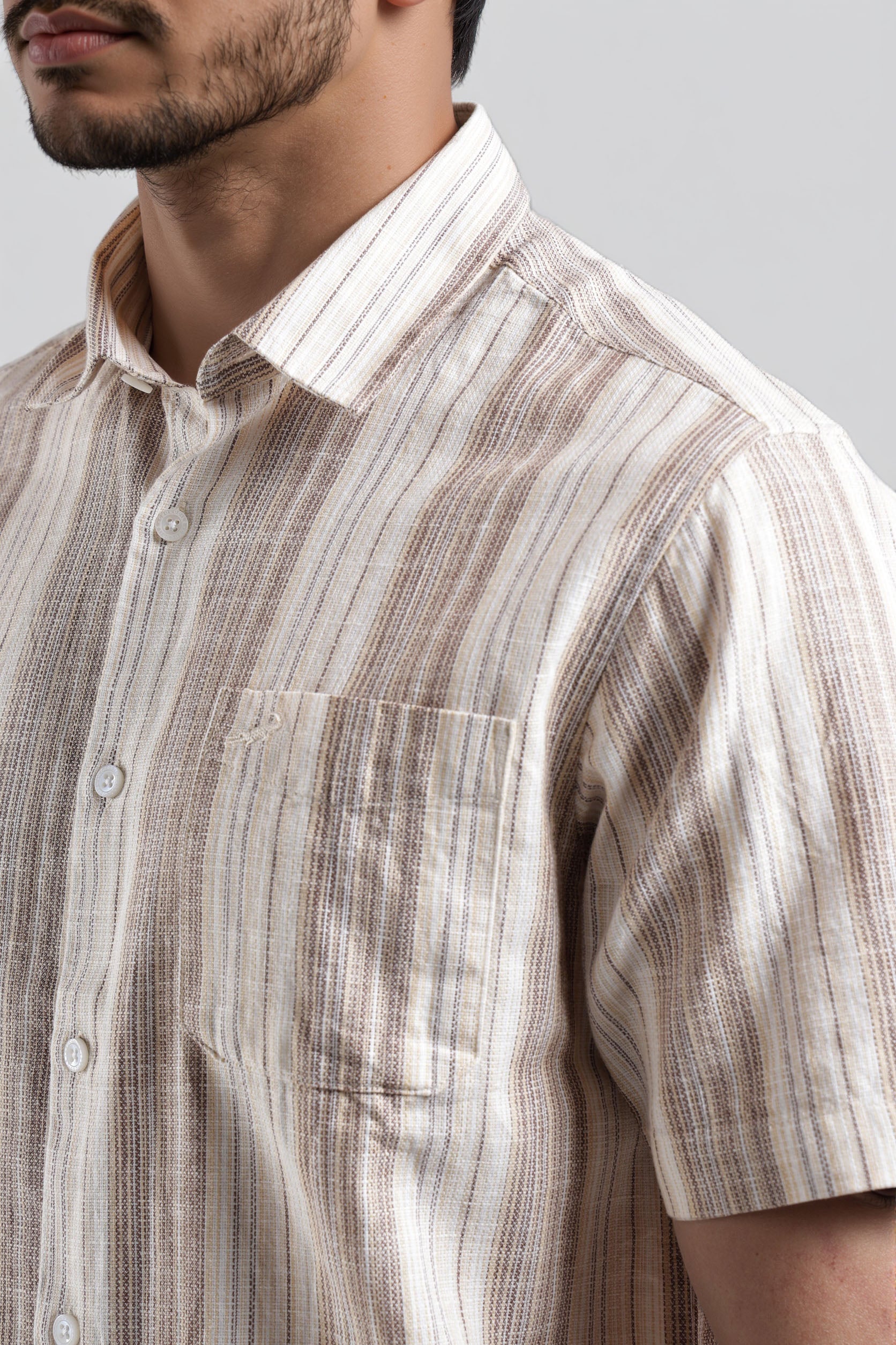 Close-up of a man wearing a patterned shirt with a neutral background