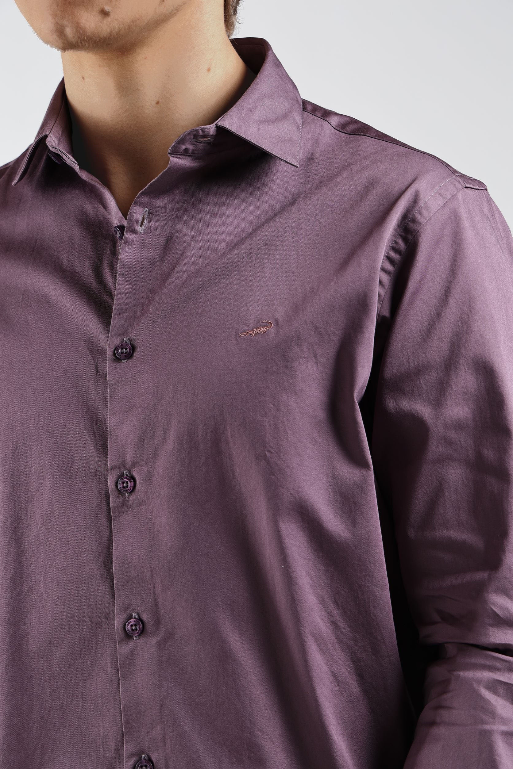 Close-up of a person wearing a purple shirt with a brand logo on a white background