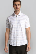 Man wearing a white patterned shirt against a gray background