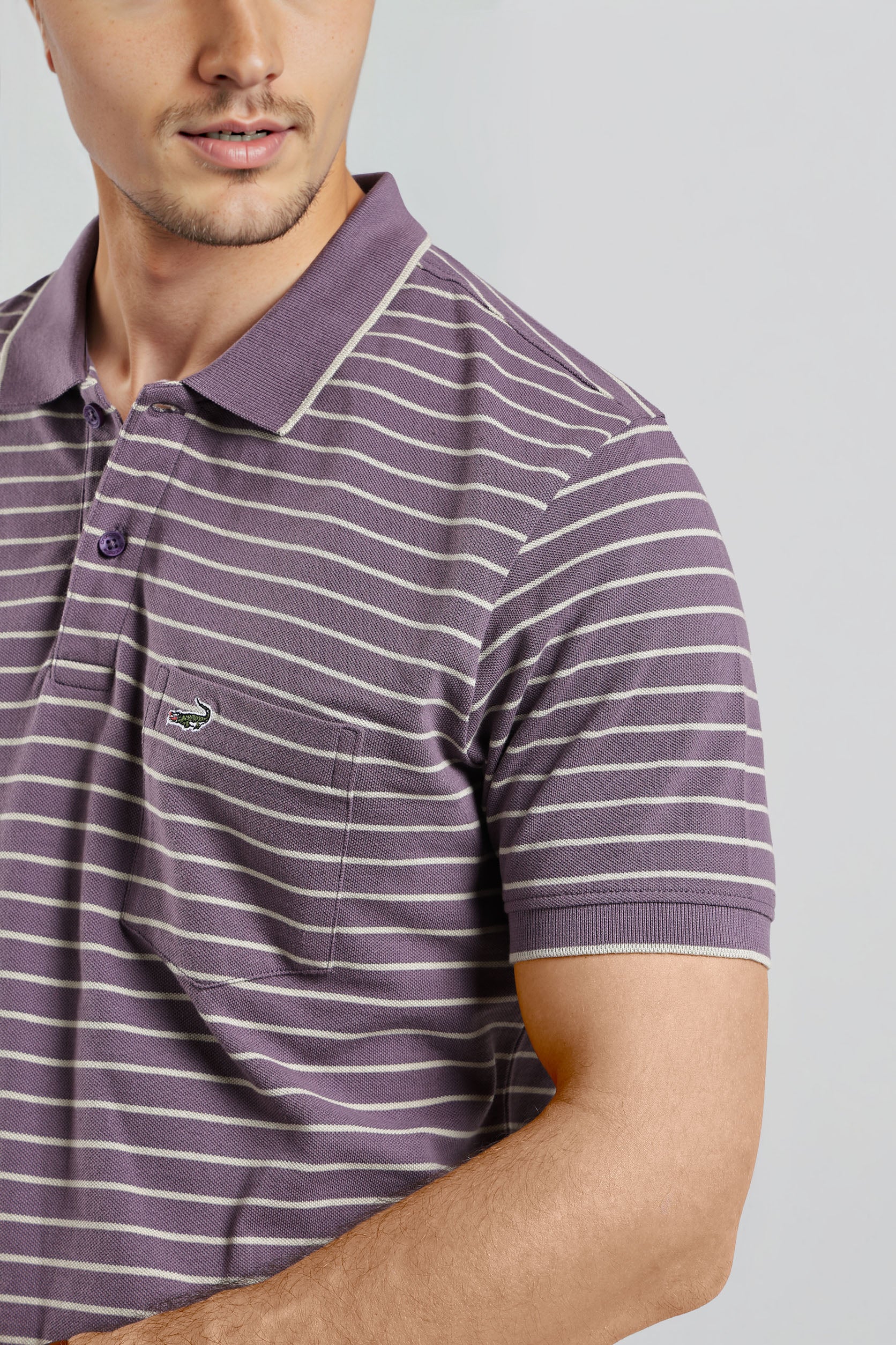 Man wearing a purple and white striped polo shirt on a gray background