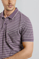 Man wearing a purple and white striped polo shirt on a gray background