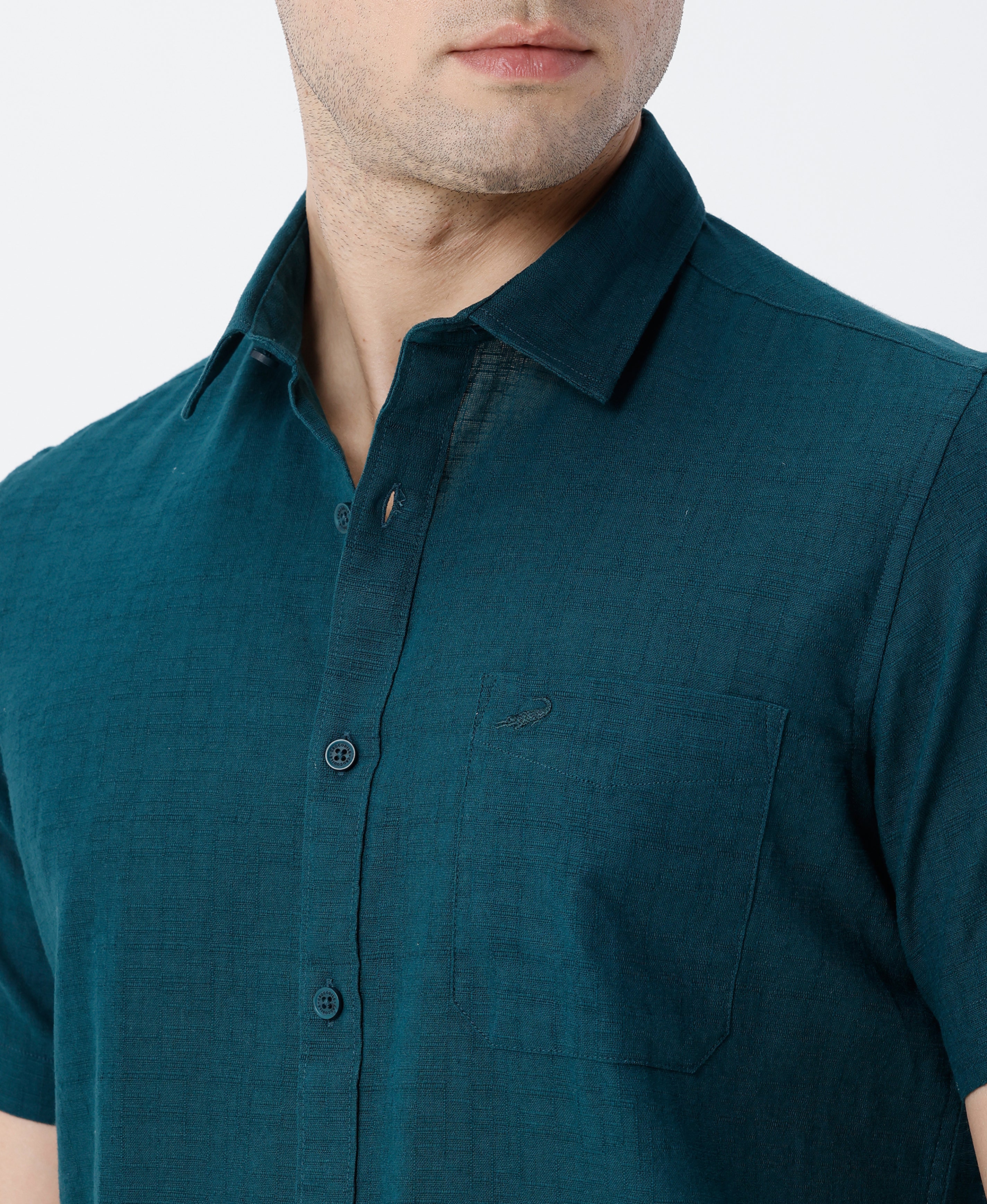Man wearing a green pure cotton textured shirt green with casual styling on a gray background