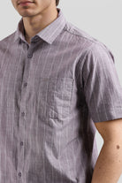 Man wearing a short-sleeve, button-up shirt with a subtle pattern against a neutral background
