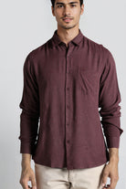 Man wearing a maroon button-up shirt against a plain background