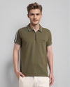 Man wearing a olive trendy stretch zipper polo with tape in olive with casual styling on a gray background