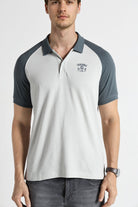 Man wearing a white and navy polo shirt with a visible brand logo on a white background