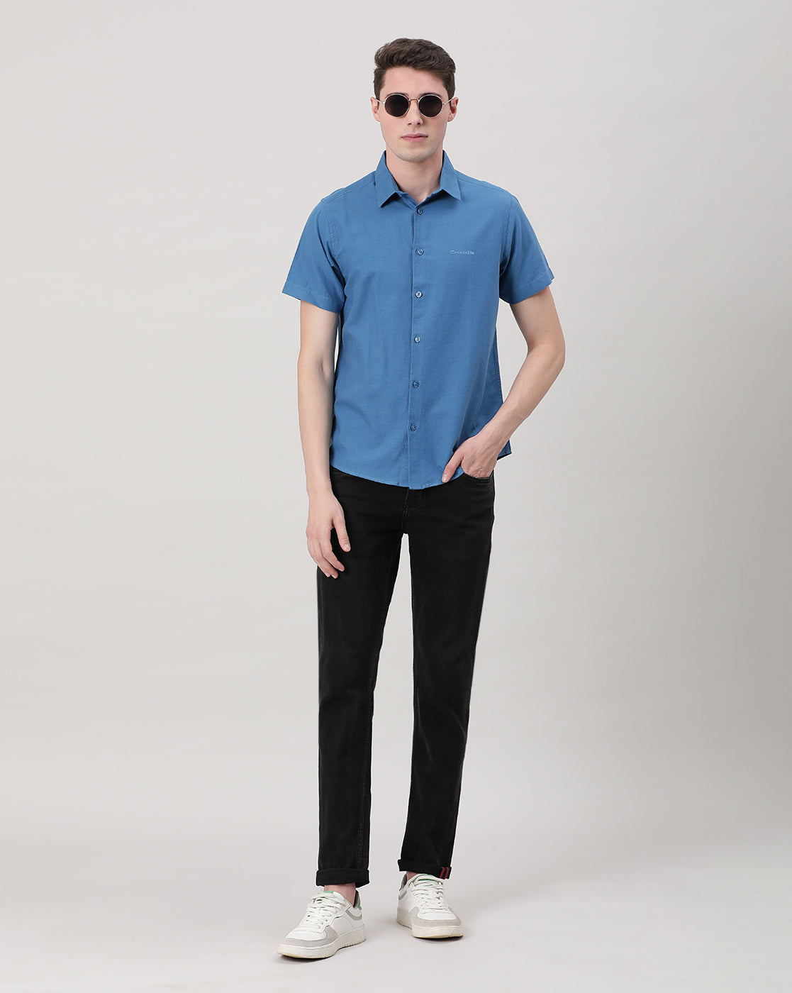 Man wearing a blue royal blue solid half sleeve linen shirt on a light gray background
