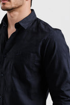 Close-up of a person wearing a dark blue shirt against a light background