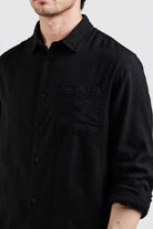 Black button-up shirt worn by a person on a plain background