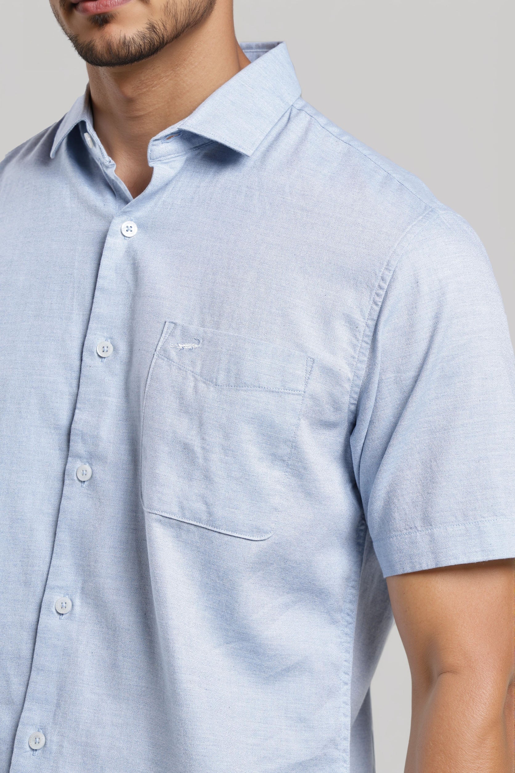 Light blue short-sleeve shirt worn by a person on a neutral background