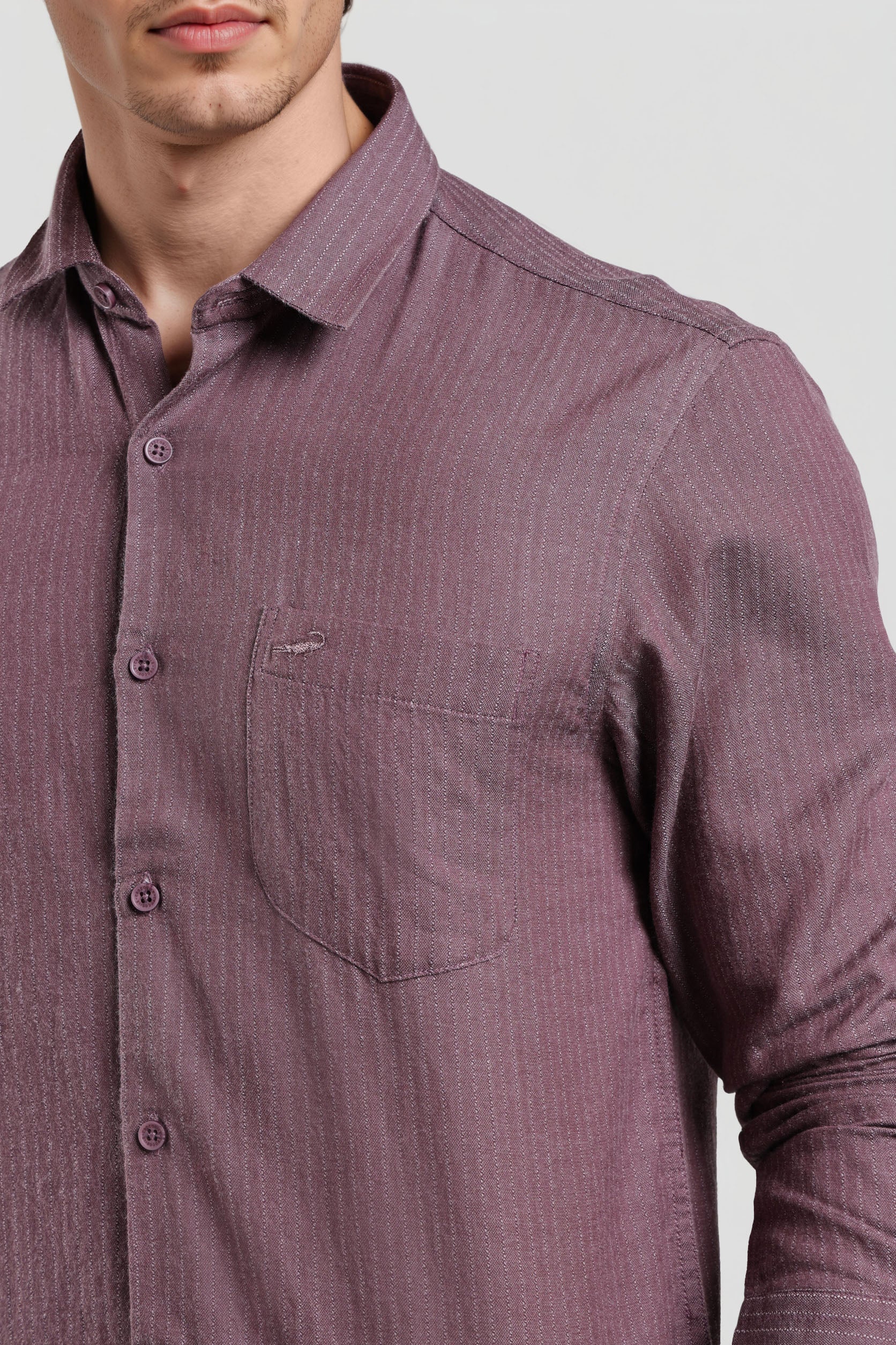Close-up of a purple button-up shirt with a pocket on a light gray background
