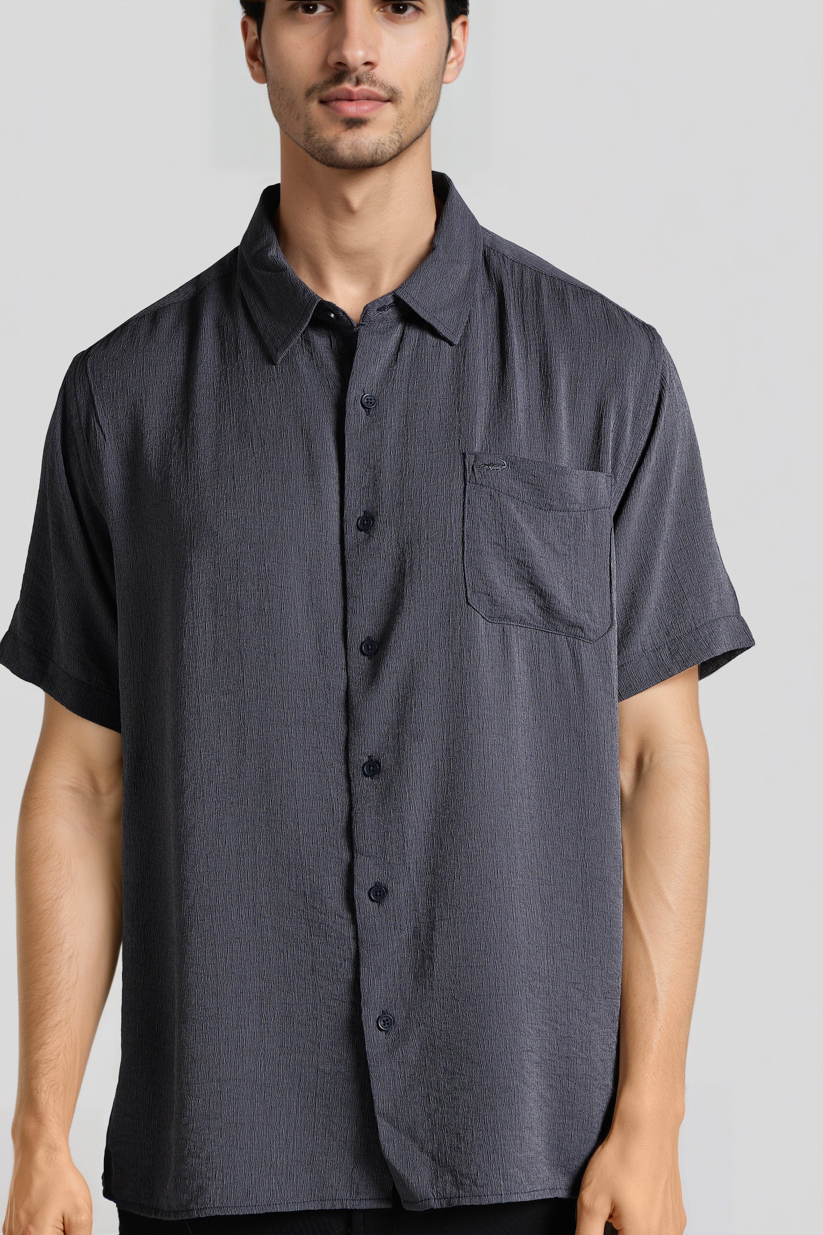 Man wearing a dark gray short-sleeve button-up shirt on a light gray background