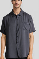 Man wearing a dark gray short-sleeve button-up shirt on a light gray background