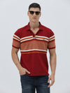 A man wearing a red short-sleeve polo shirt with horizontal cream and rust-orange stripes across the chest and sleeves, paired with dark blue jeans and black sunglasses, against a light gray studio background.
