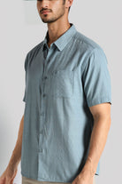 Man wearing a light blue short-sleeve button-up shirt against a plain background