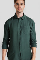 Man wearing a green shirt against a plain background
