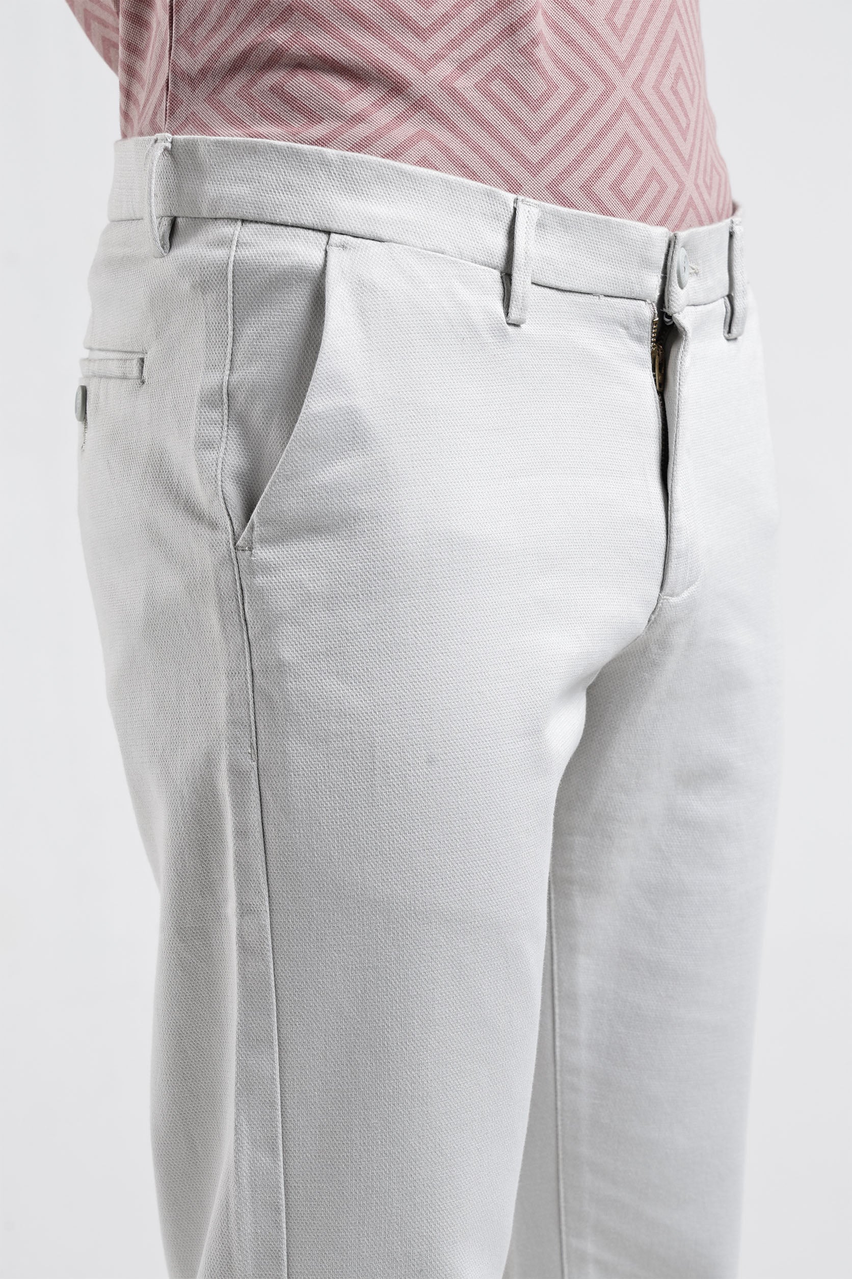 Light gray pants worn with a pink patterned shirt on a white background