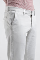 Light gray pants worn with a pink patterned shirt on a white background