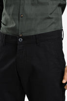 Person wearing a green checkered shirt and black pants on a white background