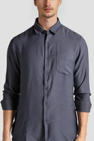 Man wearing a dark gray button-up shirt on a light gray background