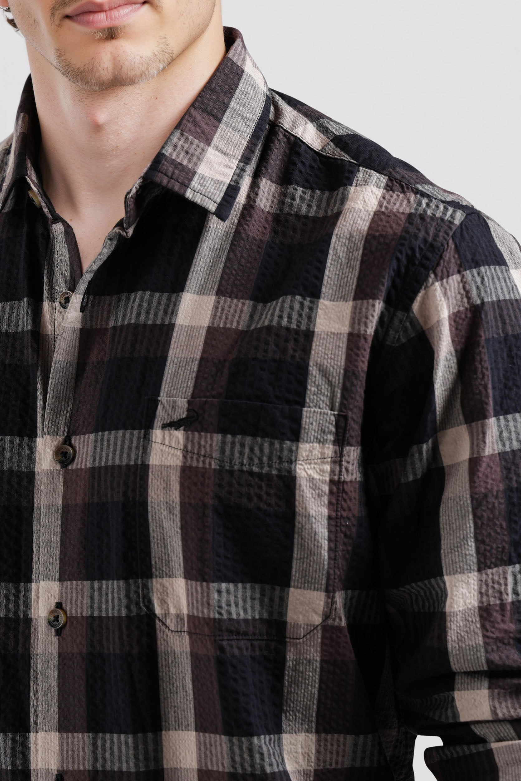 Close-up of a person wearing a plaid shirt with a neutral background