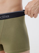 Person wearing olive green boxer briefs with a black waistband featuring the brand name.