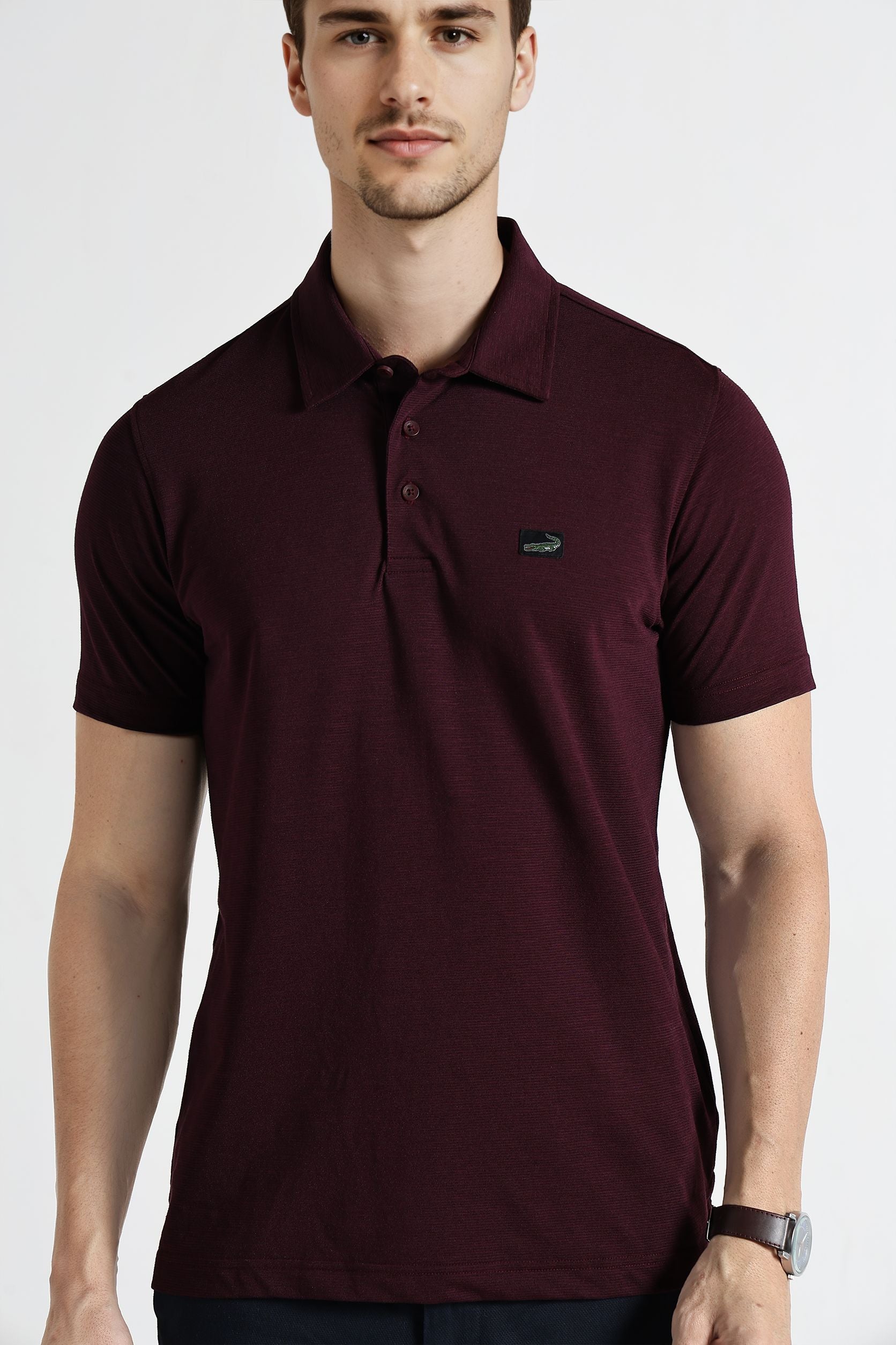 Man wearing a maroon polo shirt with a logo on a white background