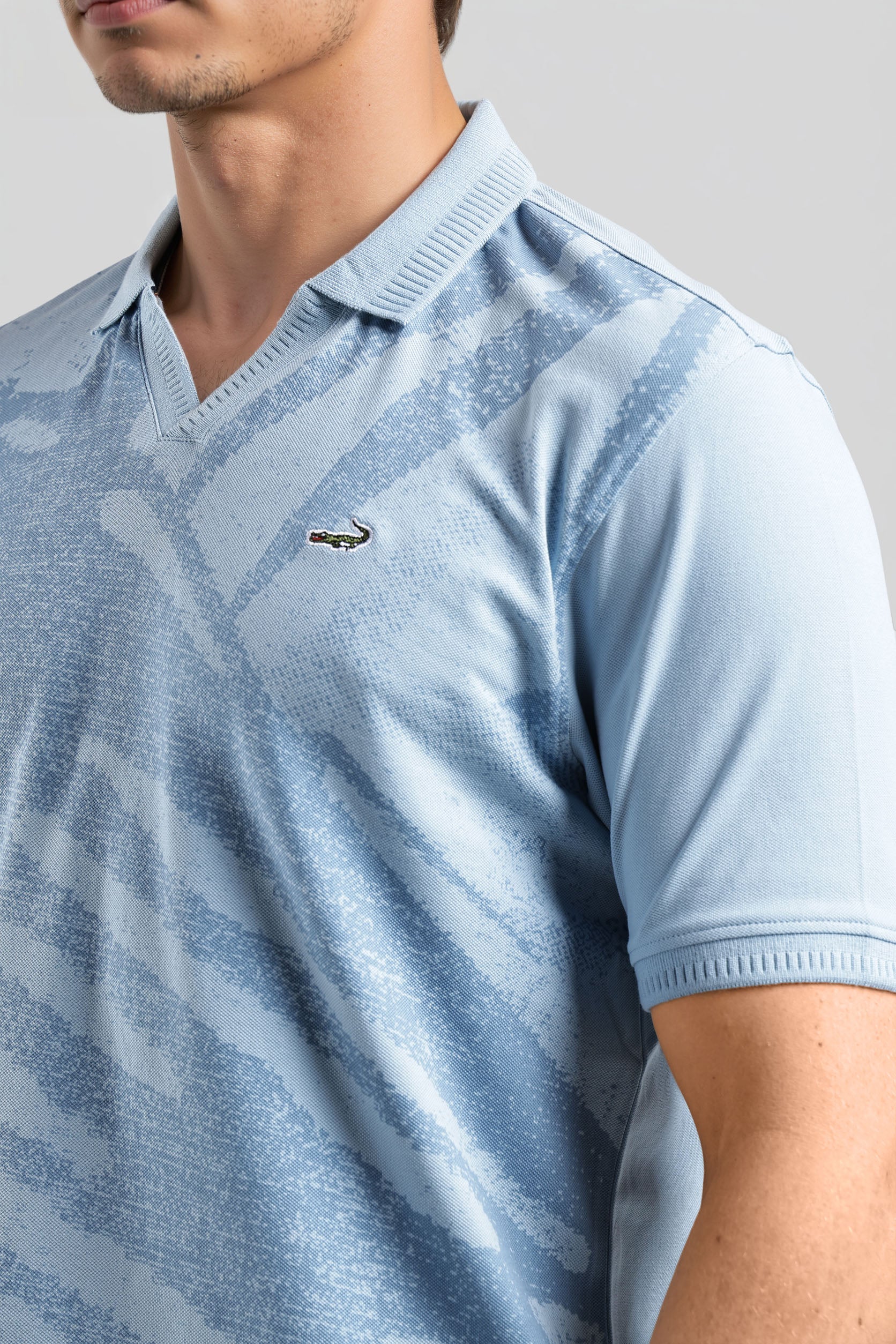 Light blue patterned polo shirt worn by a person on a gray background