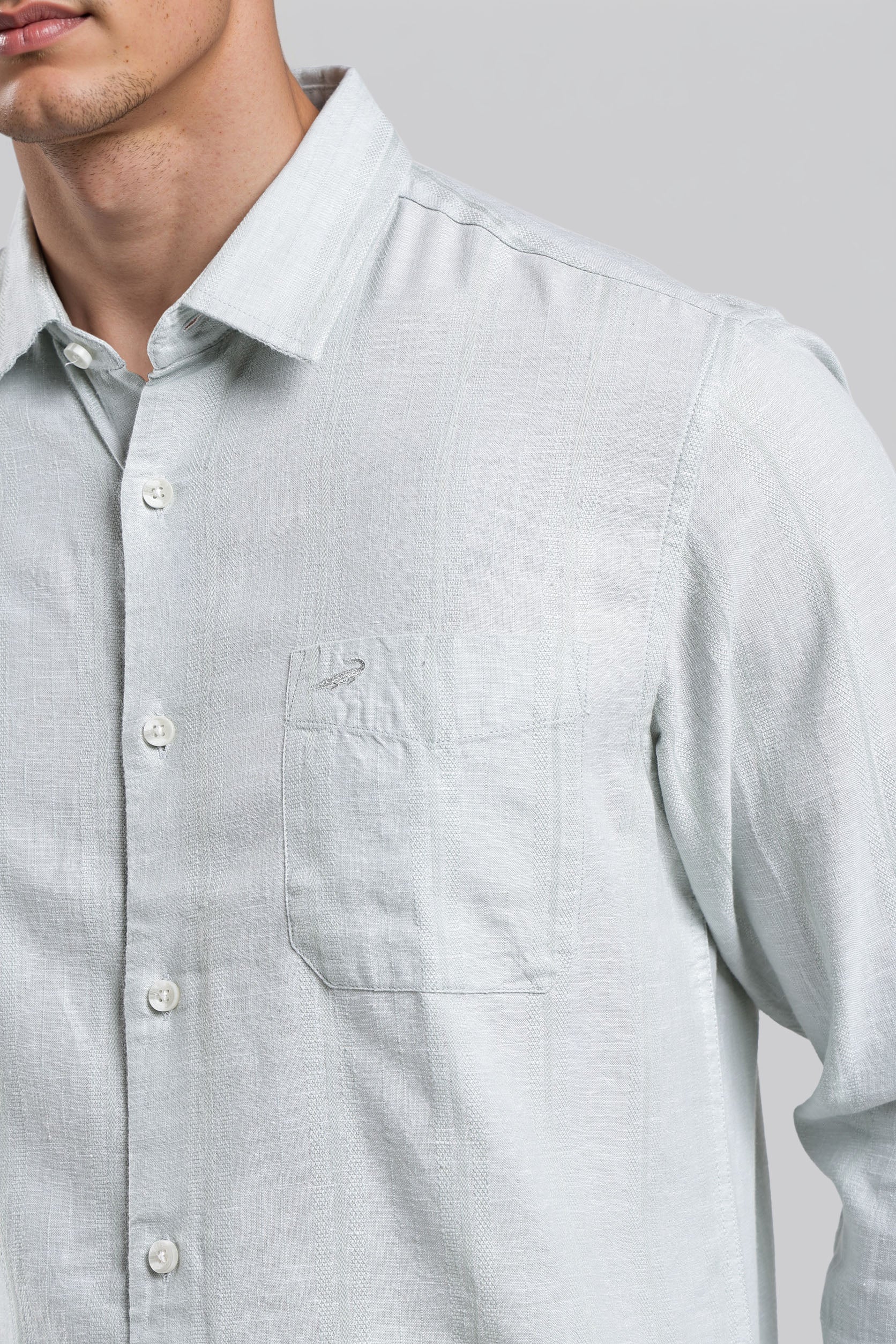 Light gray button-up shirt worn by a person on a plain background