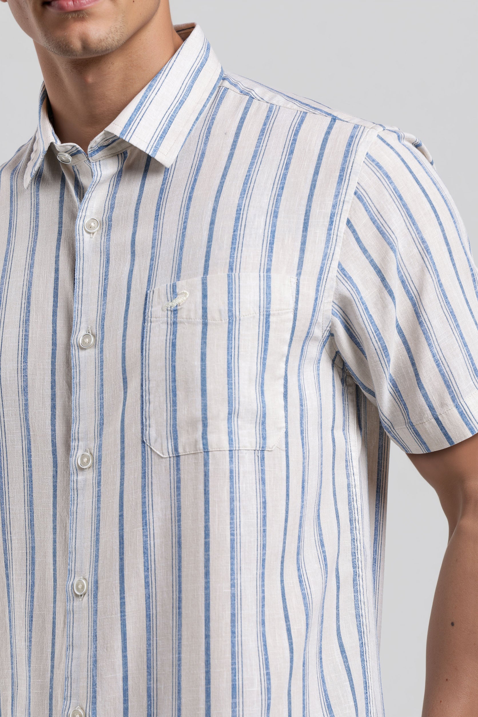 Man wearing a short-sleeve shirt with blue and white stripes on a plain background