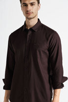Man wearing a brown button-up shirt against a white background