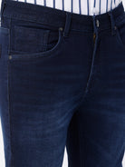 Man wearing a blue dark blue knit slim fit jeans with casual styling on a gray background