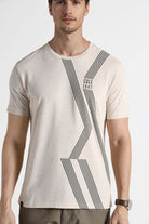 Man wearing a beige t-shirt with black geometric design on a white background
