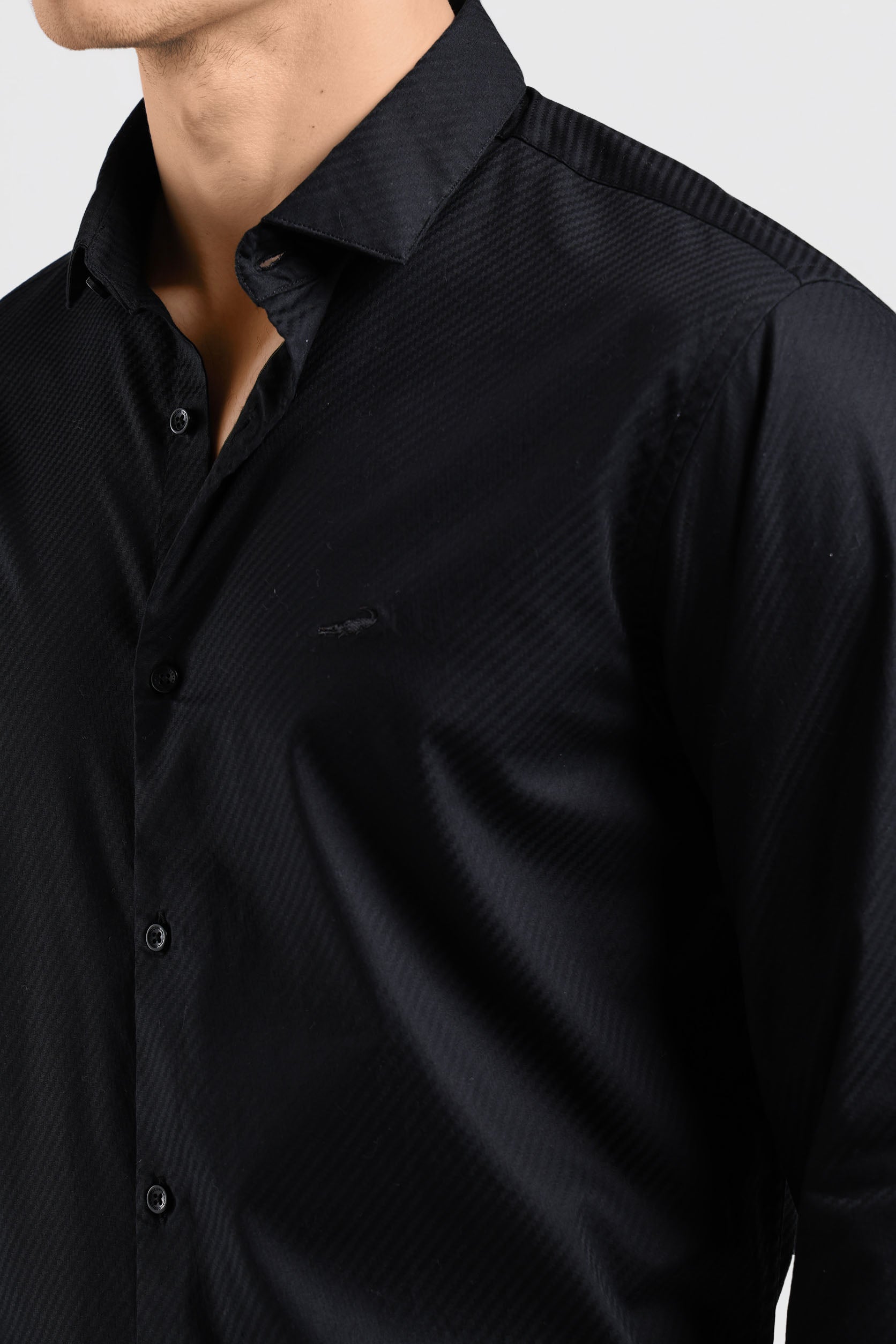 Close-up of a black shirt with a collar and buttons on a light gray background